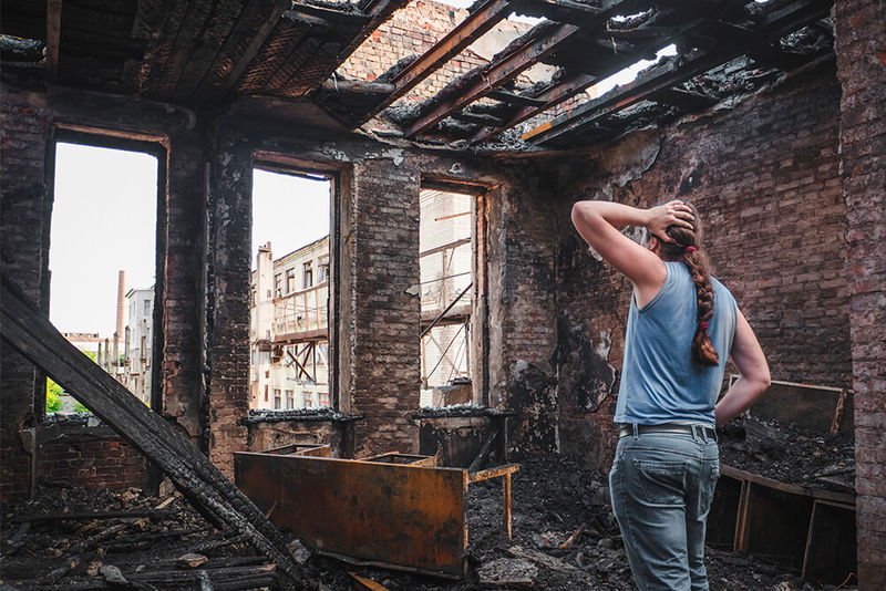 Ein Mann steht verzweifelt in den Überresten eines abgebrannten Wohnhauses